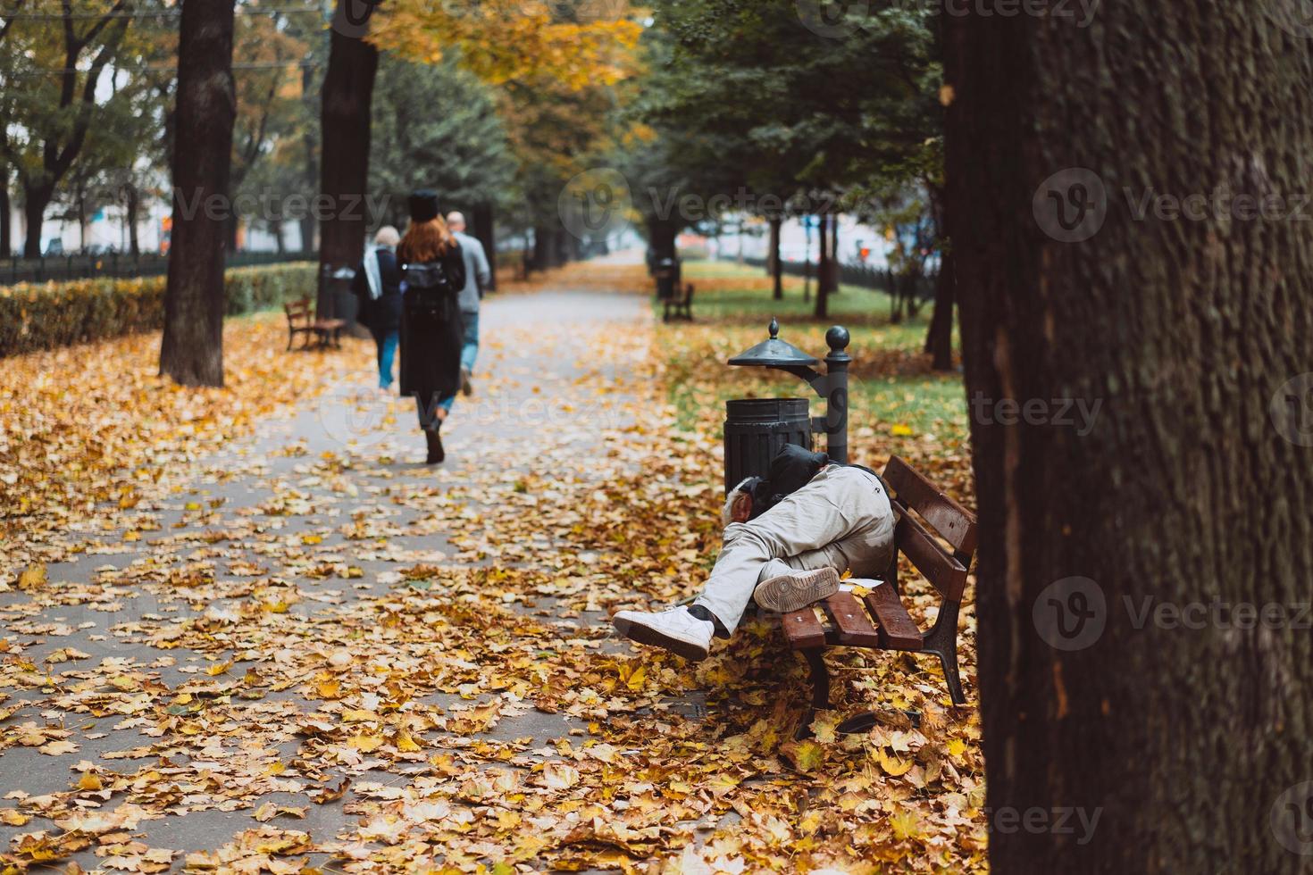 Homeless sleeping on the benches in the autumn park photo