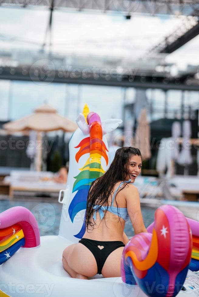Woman on inflatable unicorn toy mattress float in pool. photo