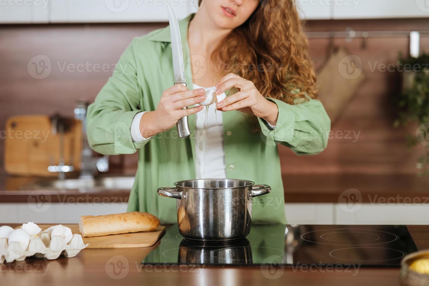 Young woman is preparing food in the kitchen. Beating eggs. photo