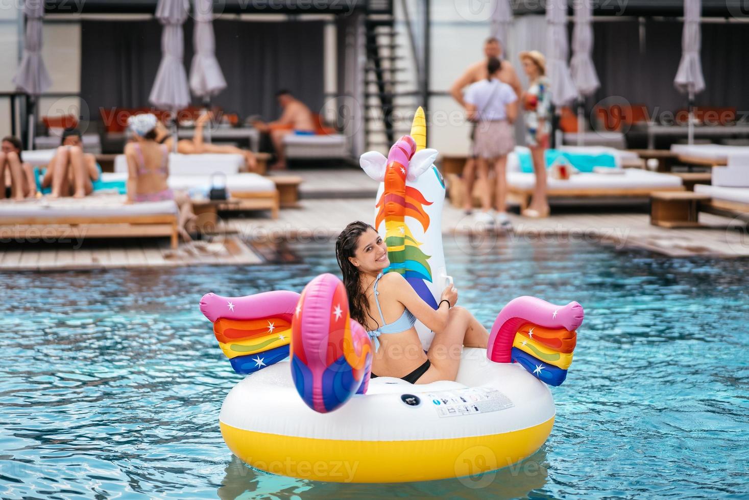 Woman on inflatable unicorn toy mattress float in pool. photo