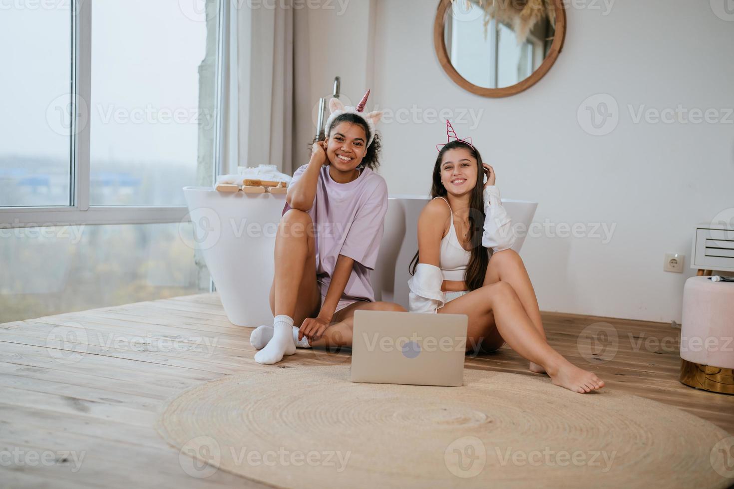 Young women on the bathroom floor looking at a camera photo