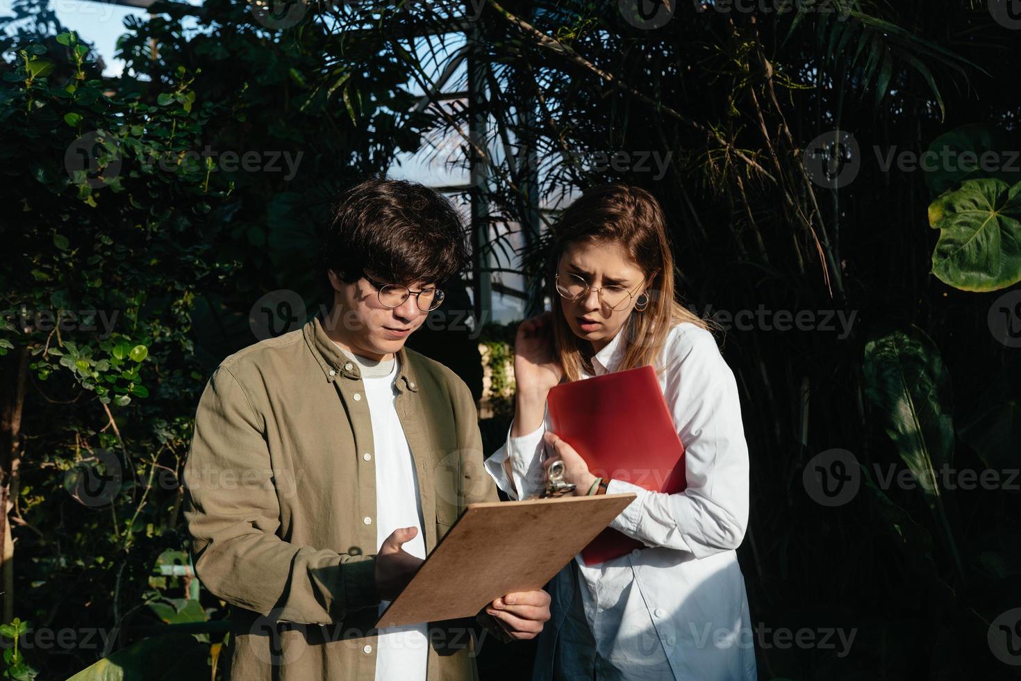 Young agricultural engineers talk in greenhouse photo