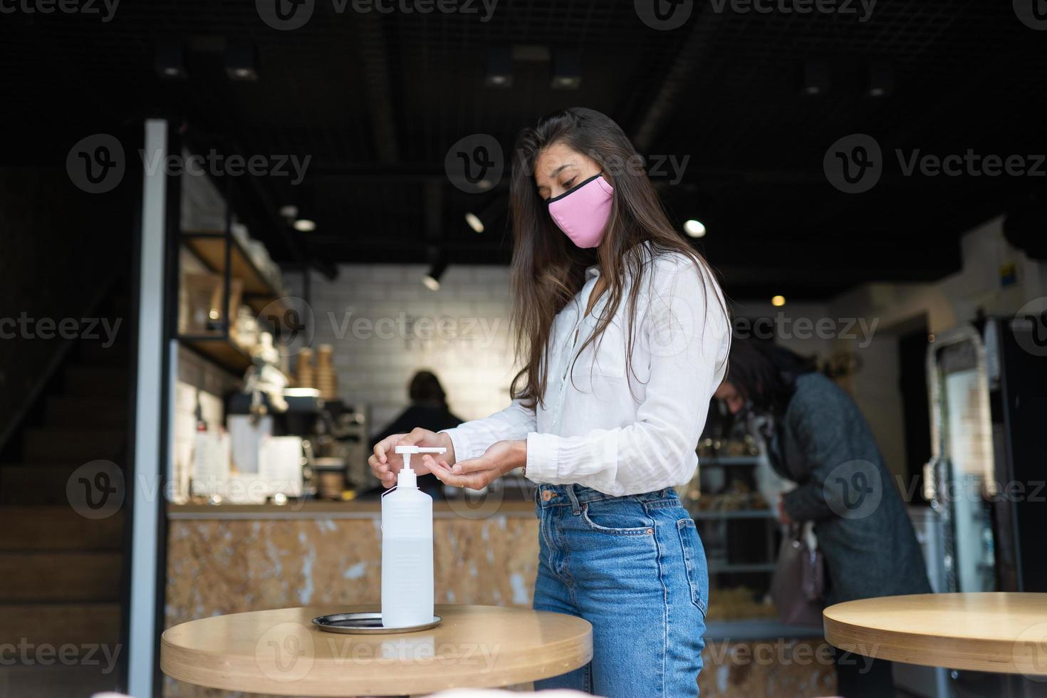 Woman using sanitizer gel cleans hands of coronavirus virus at cafe. photo