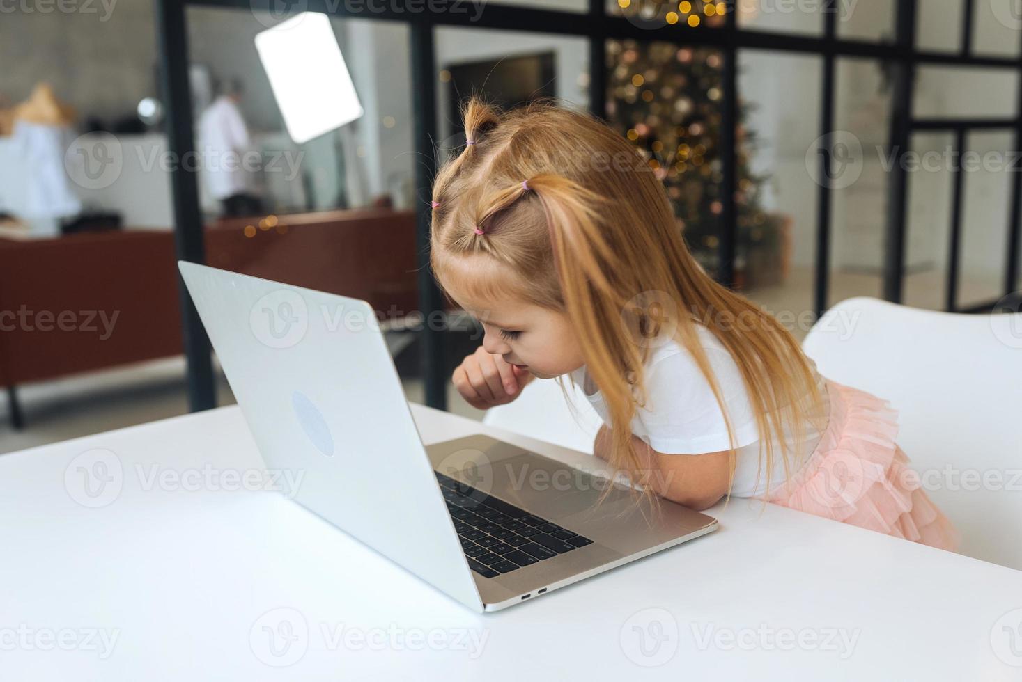 Little girl using tablet computer sitting at table photo