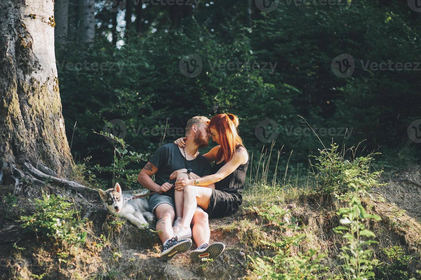 beautiful couple sitting in a forest near the tree photo