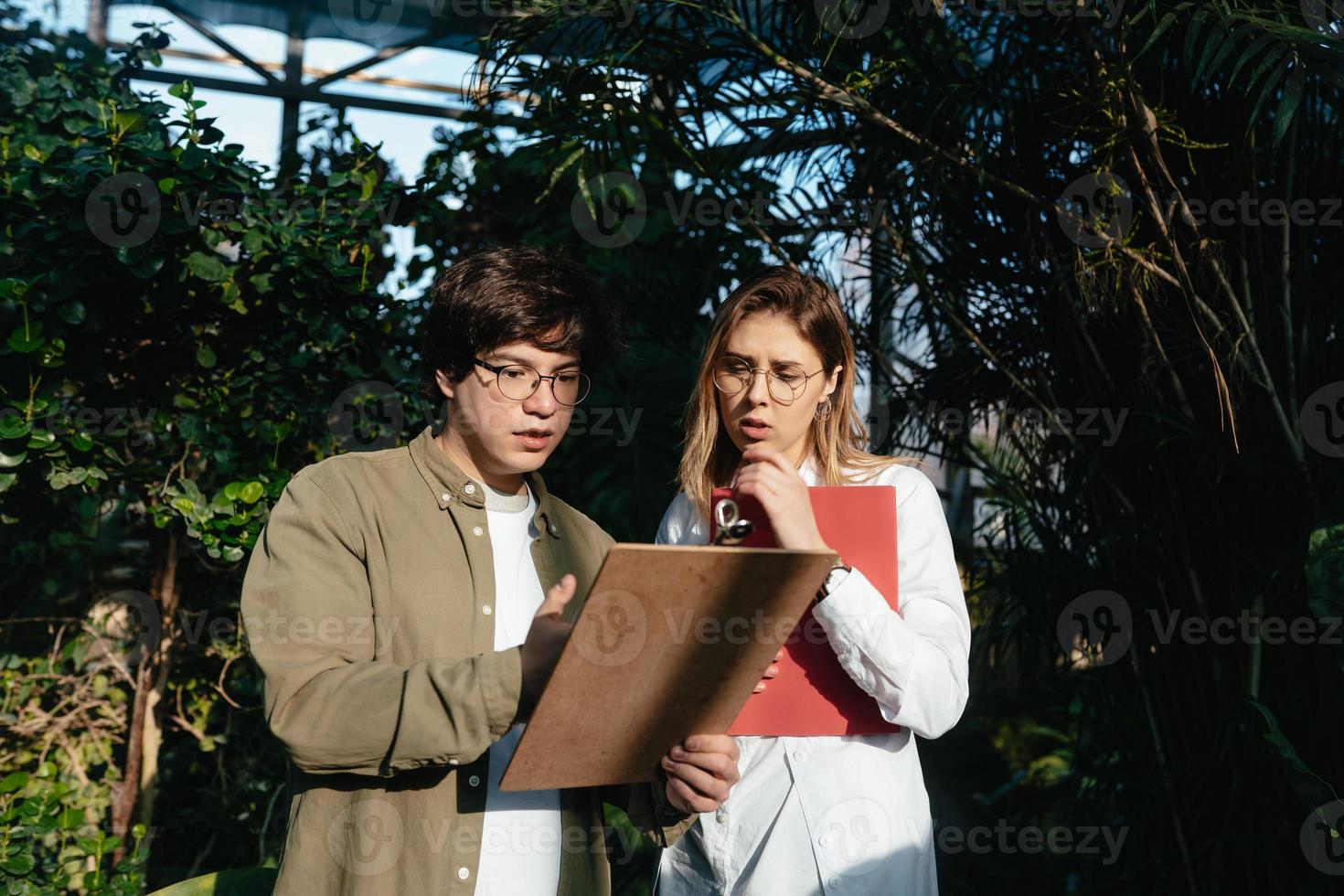 Young agricultural engineers talk in greenhouse photo