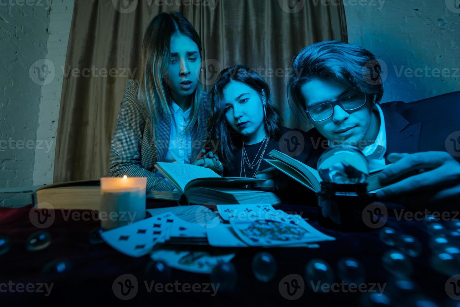 Two women and a guy are reading a mysterious books, close view photo