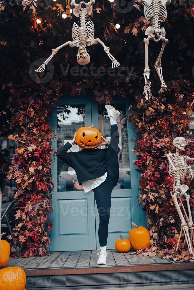 Girl with a pumpkin head posing at the door on the street photo