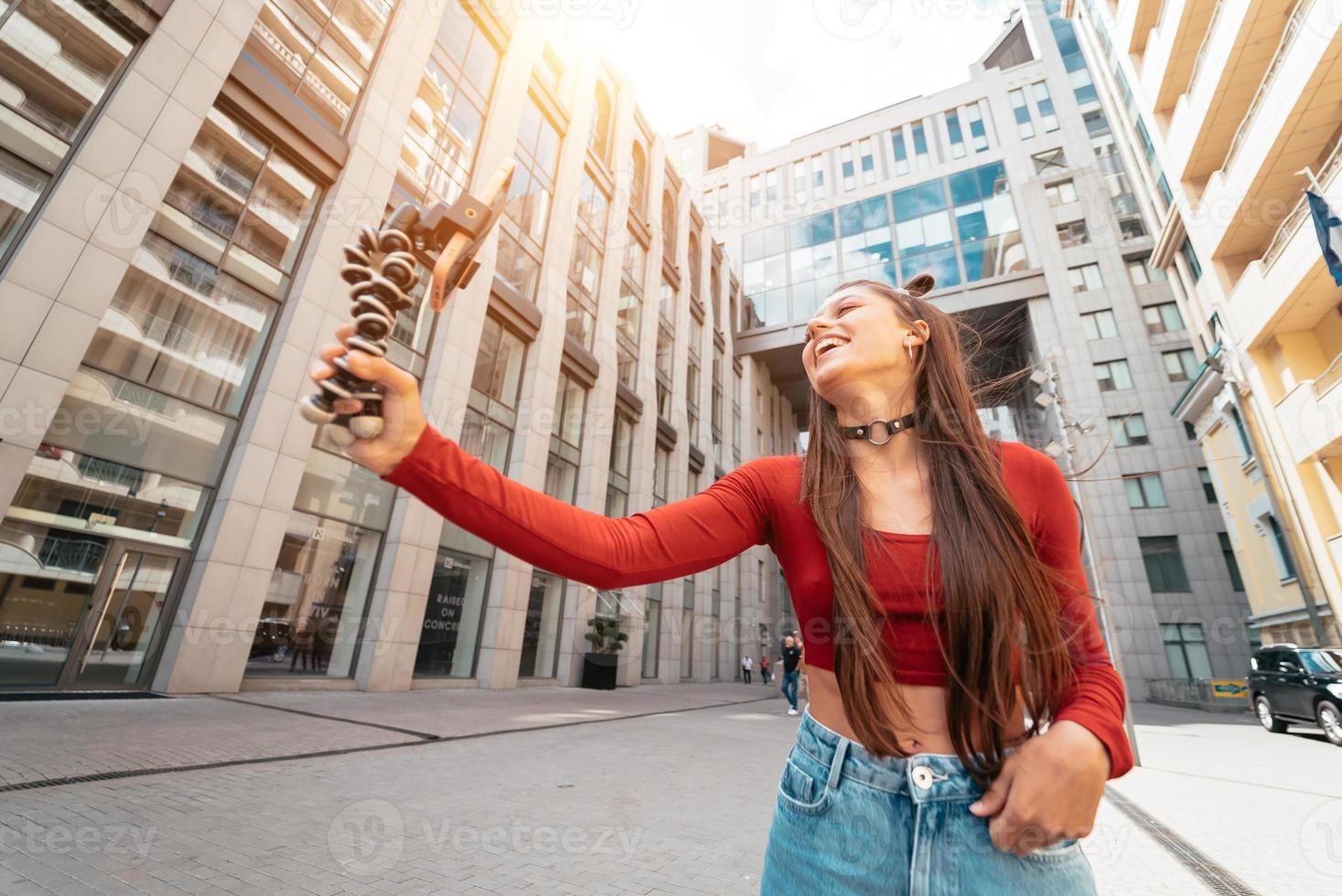 Young female blogger with smartphone streaming on the street. photo