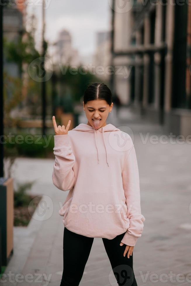 Playful portrait of pretty young woman, having fun at the street. photo