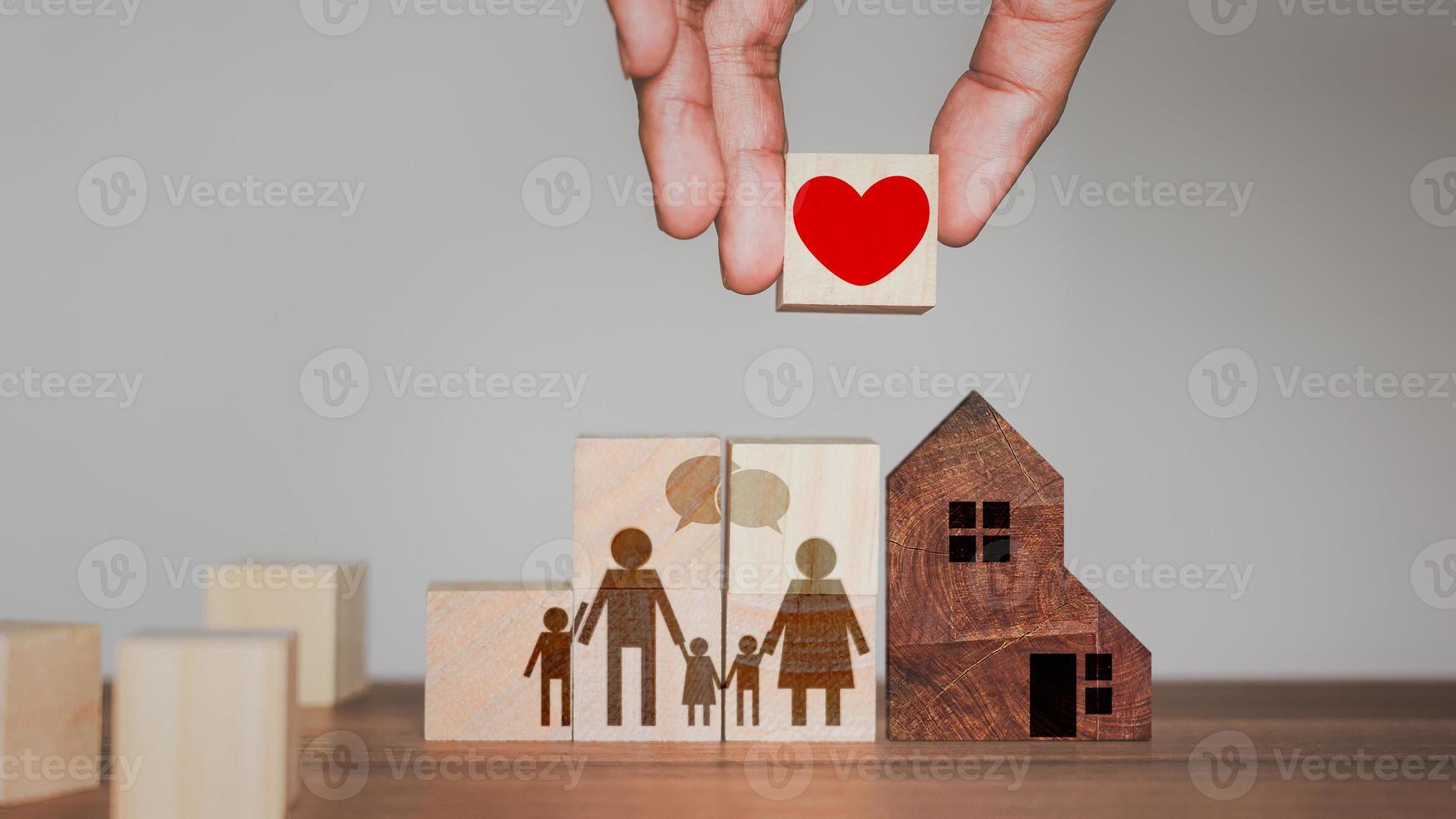 idea de añadir amor y calidez a la familia. mano sosteniendo un bloque de cubo de madera con un icono de corazón rojo para la familia. foto