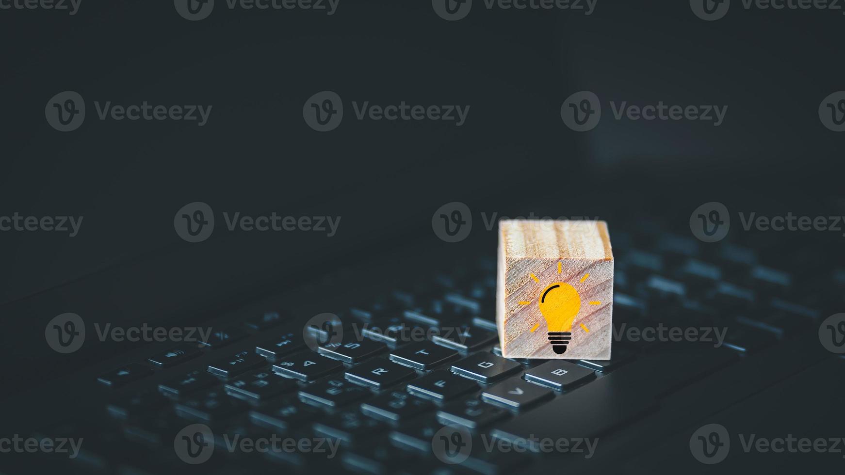 Light bulb creative idea icon on wooden cube block  which is placed on a laptop. photo