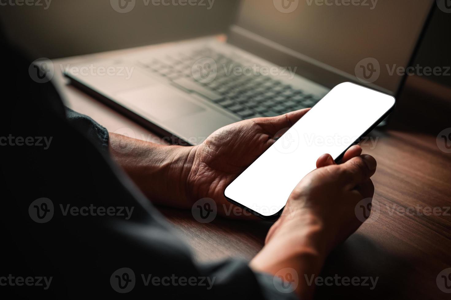 Mockup image of a man holding and using smartphone with blank desktop screen while working and drinking coffee in cafe. photo