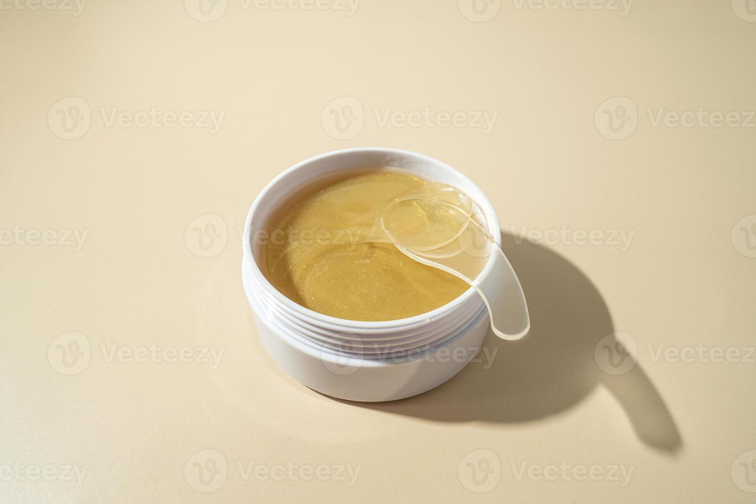 Golden antiaging eye patches with the snail extract lying on a beige background photo