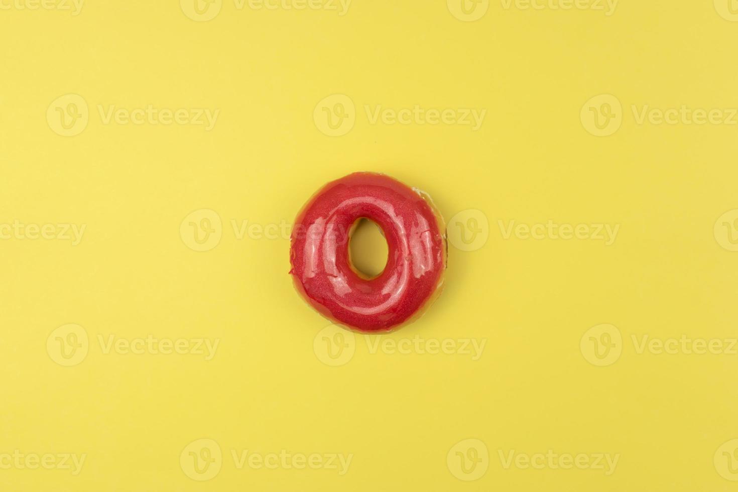 A tasty glazed donut lies on a yellow background photo