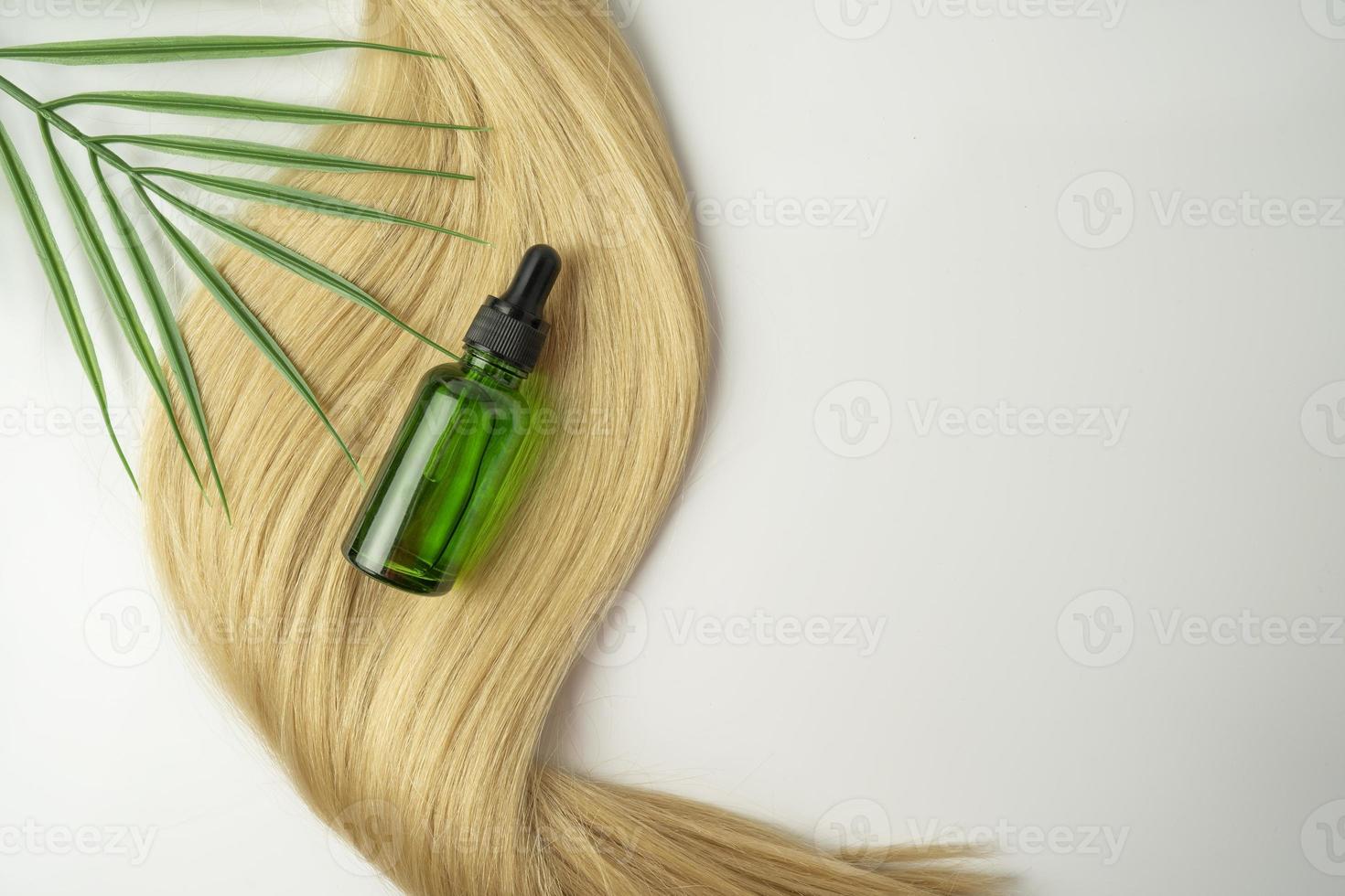 A natural oil or serum for hair care lying on a ply of blonde hair photo