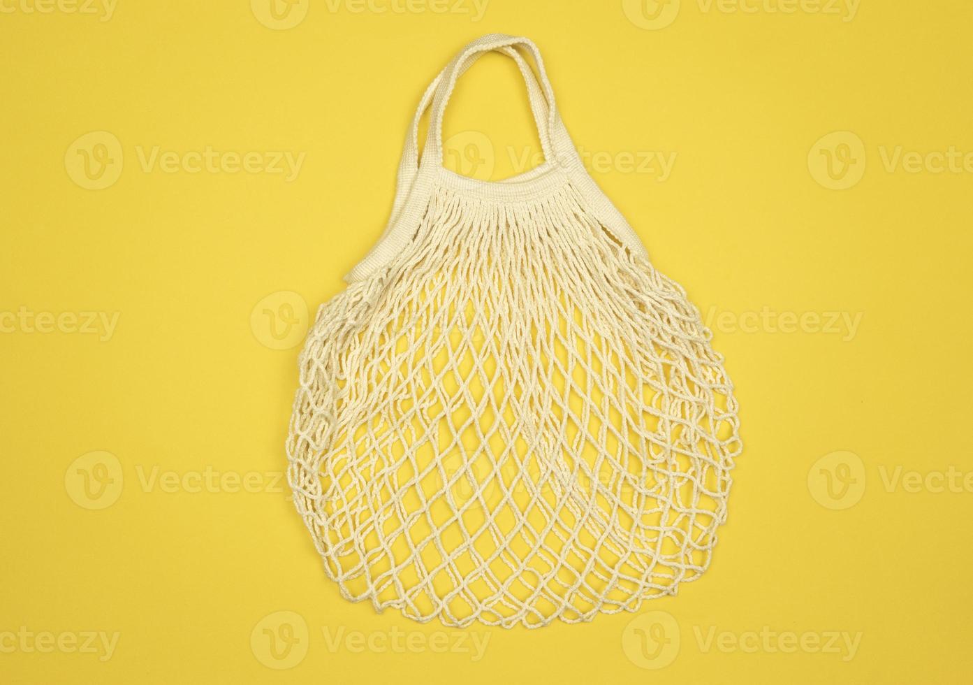 A white mesh empty bag lies on a yellow background photo