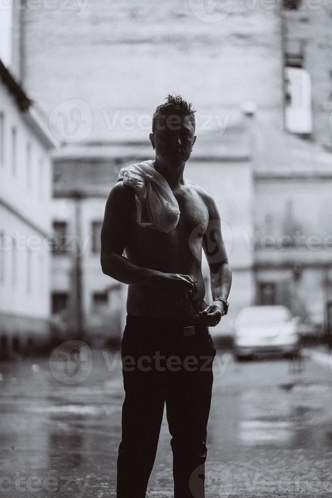 Portrait of carefree handsome young man is feeling free under the rain photo