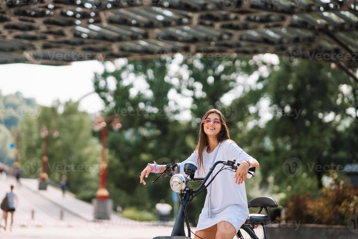 Young beautiful woman and an electric scooter, ecological transport photo