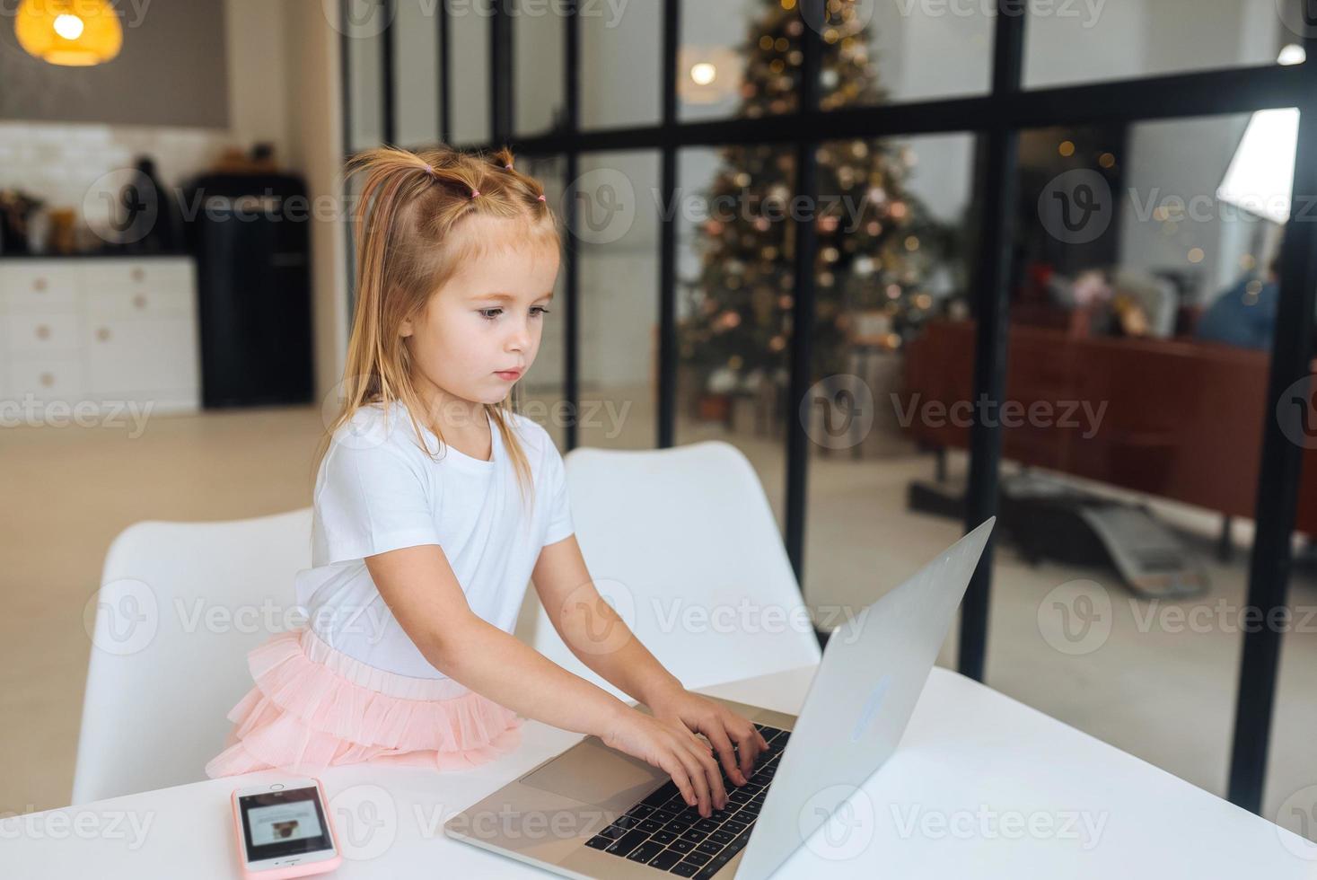 Little girl using tablet computer sitting at table photo