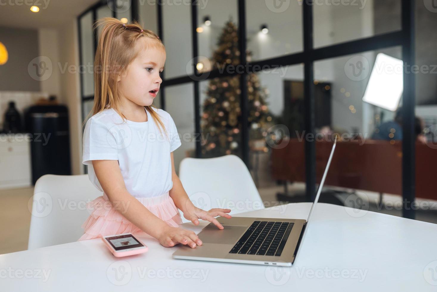 Little girl using tablet computer sitting at table photo