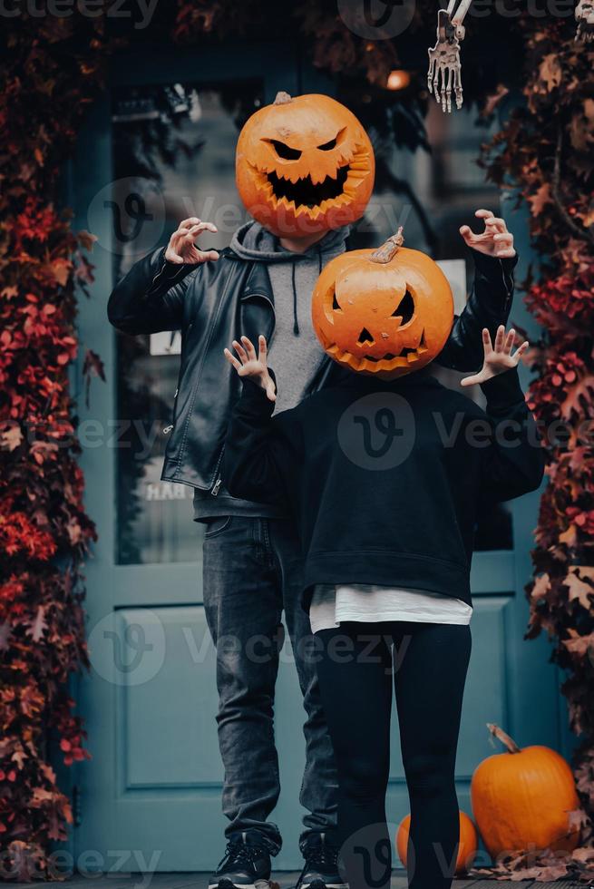 Couple with pumpkin heads scares passers-by at the camera photo