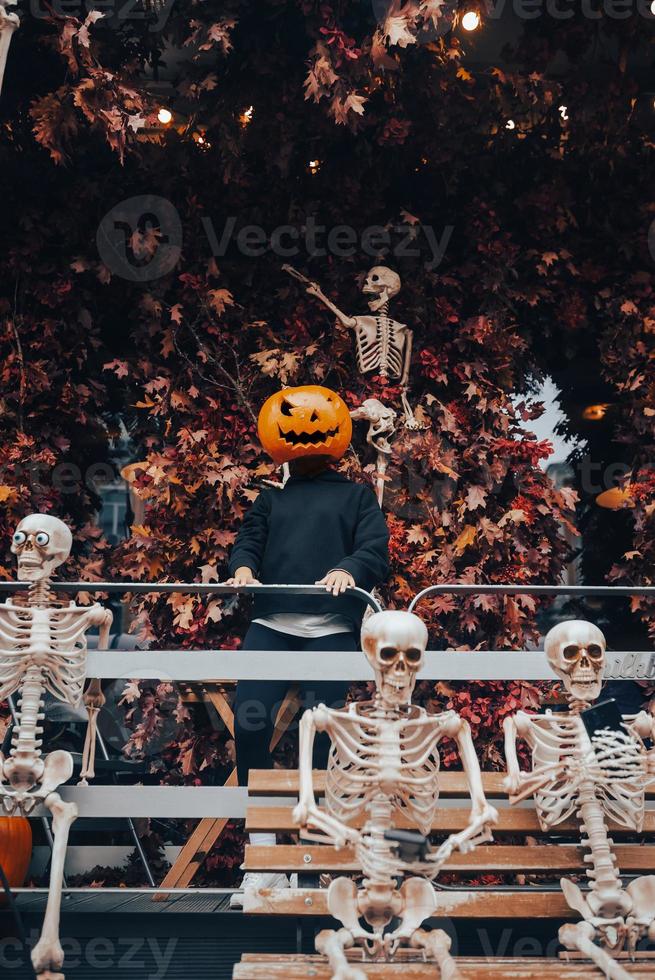 Girl with a pumpkin head posing at the street photo