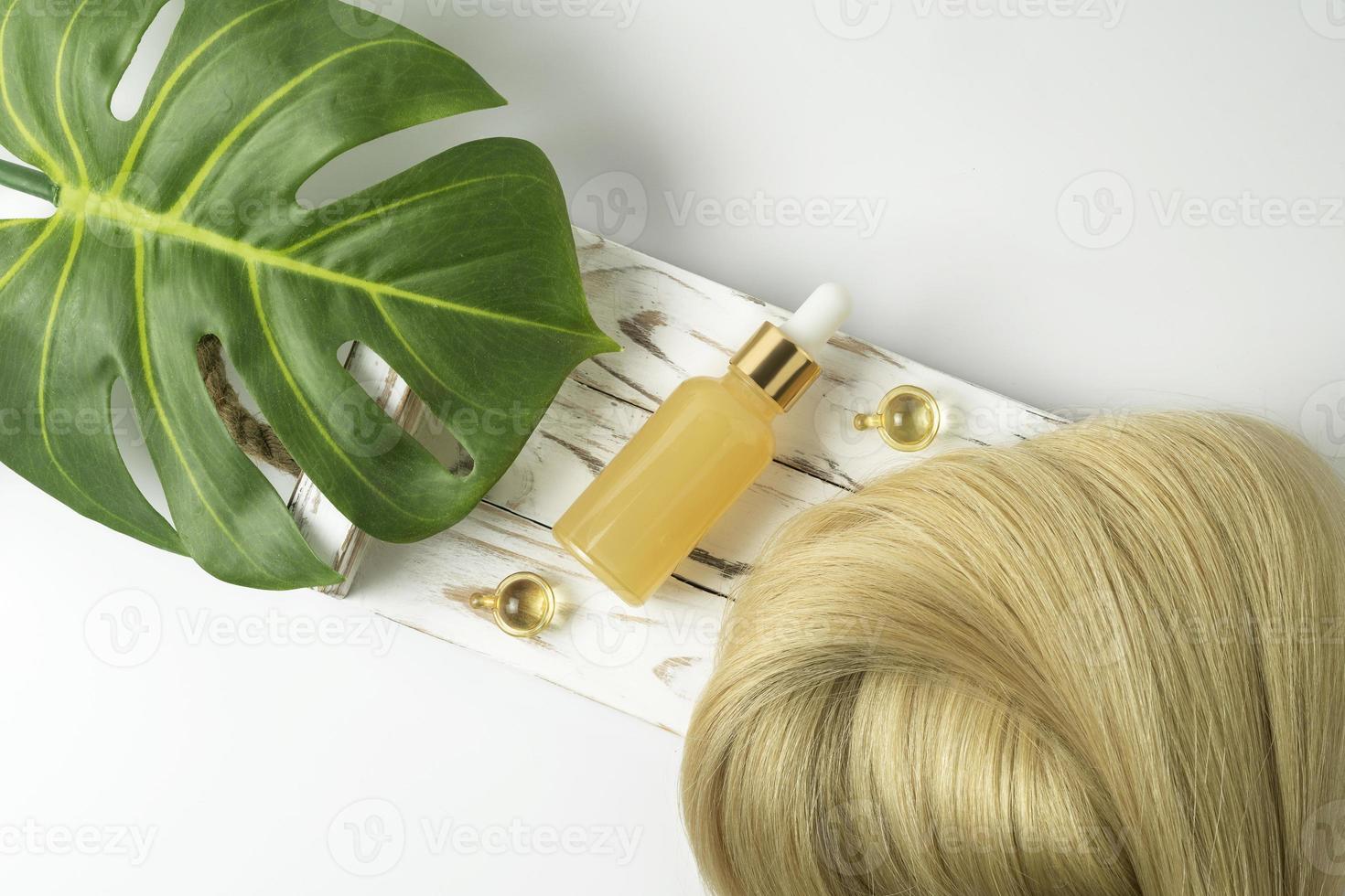 A natural essential oil or serum for hair care lying on a white wooden tray. Hair care and smoothing concept photo