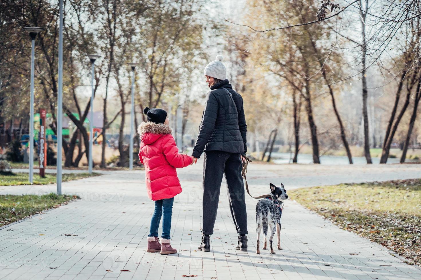 Happy mother and her daughter walk with dog in autumn park photo