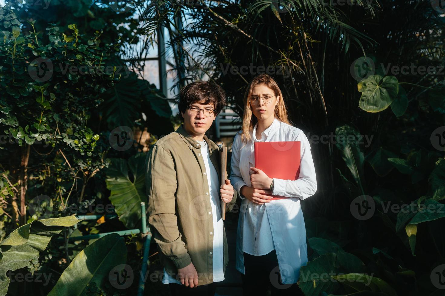 Young agricultural engineers talk in greenhouse photo