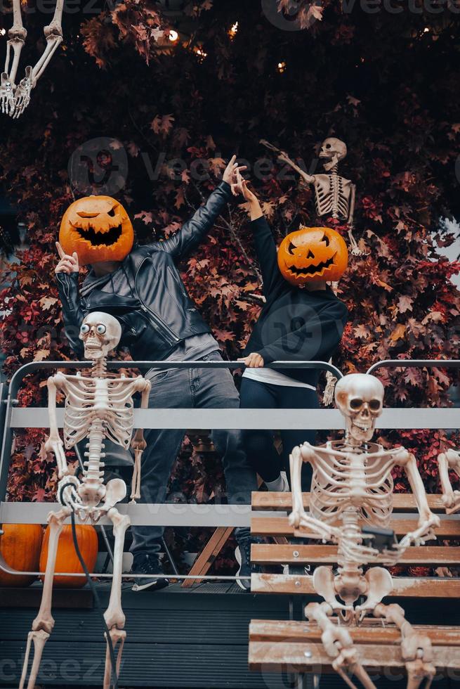 un chico y una chica con cabezas de calabaza posando en la calle foto