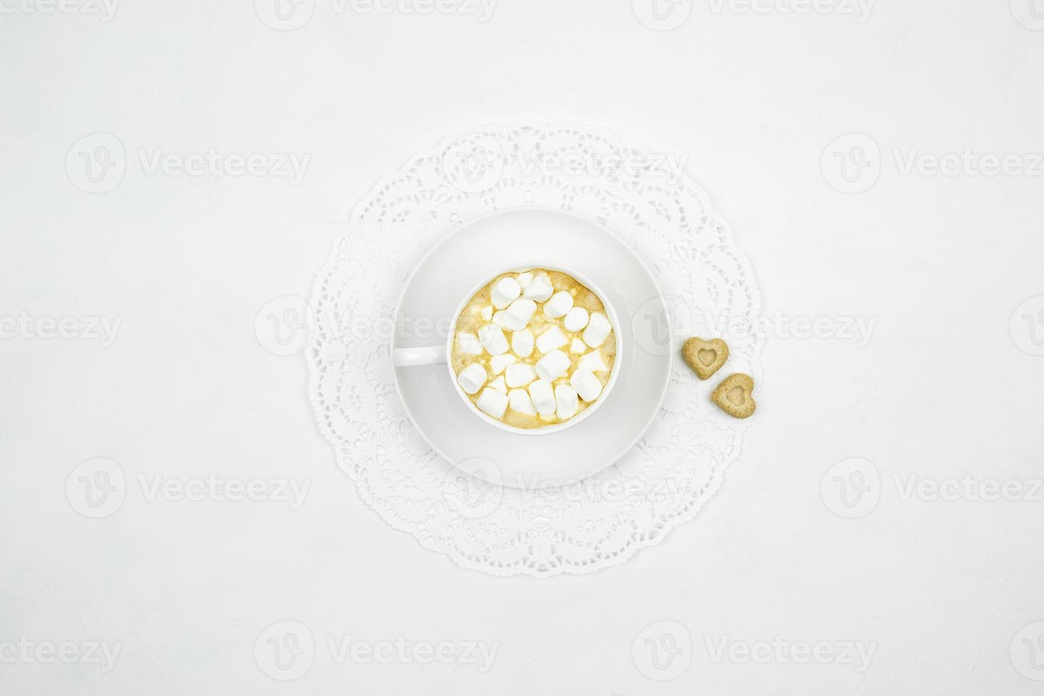 A white cup pf cappuccino with little marshmallows in it on a white background photo