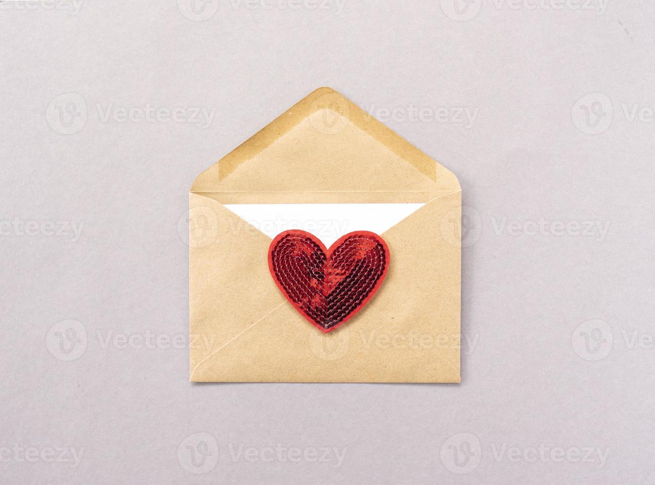 A red heart lies on a brown envelope for Valentines Day photo