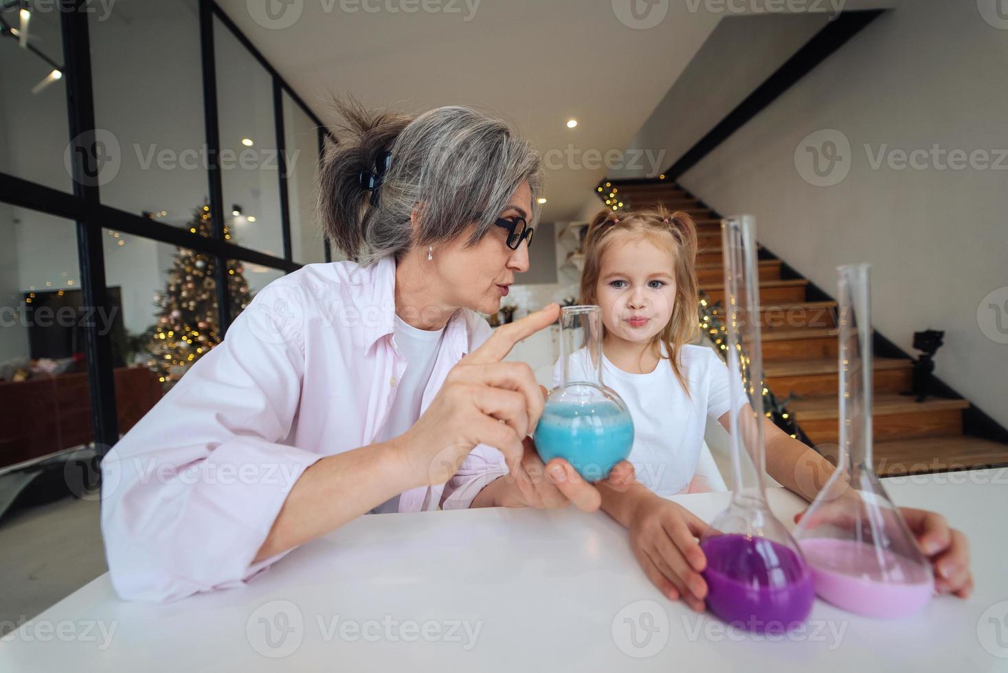 Attentive old grandma assist grandkid in funny scientific research photo