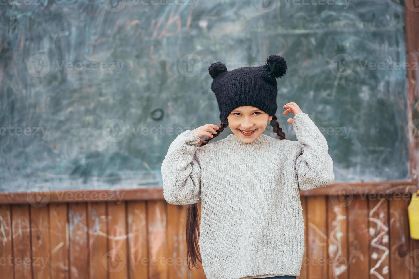 Little girl in a hat posing on the background of the school blackboard photo