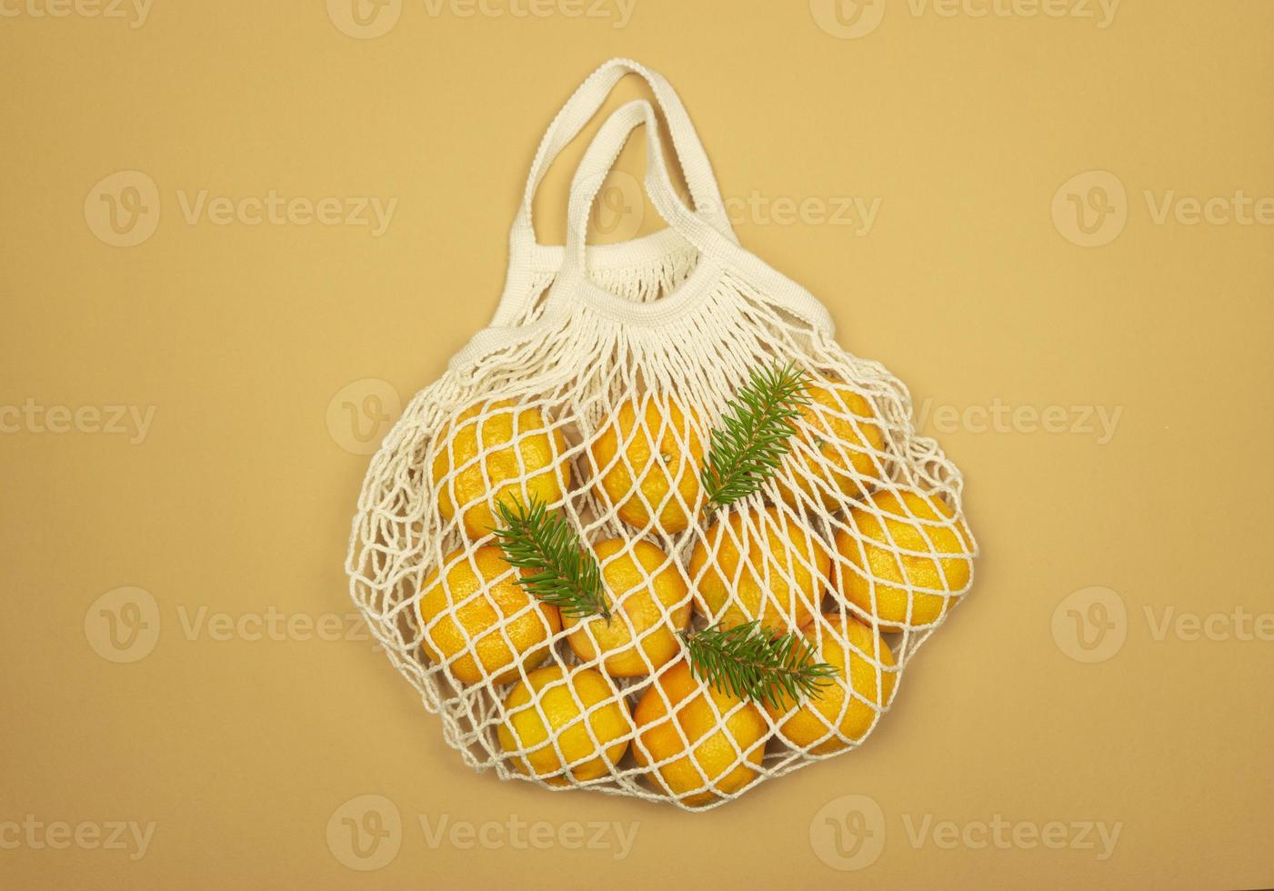A white mesh bag full of tangerines photo