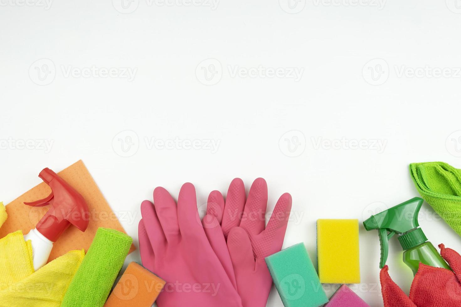 Pink rubbers, colorful sponges and cleaning supplies lie on a white table in the kitchen photo
