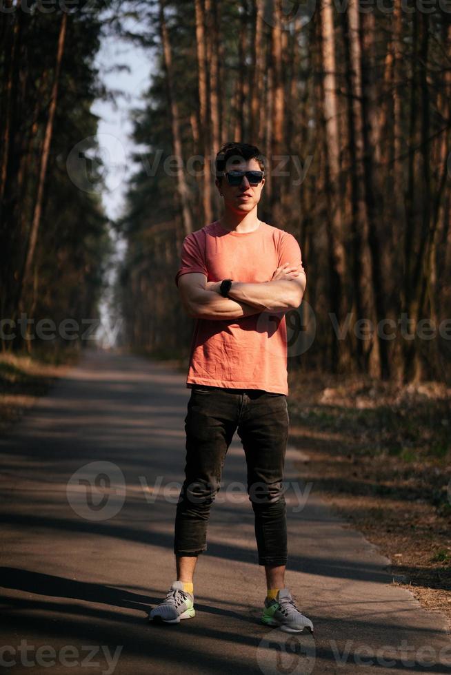 Handsome young man in white t-shirt and jeans outdoor in park, walking in the park photo
