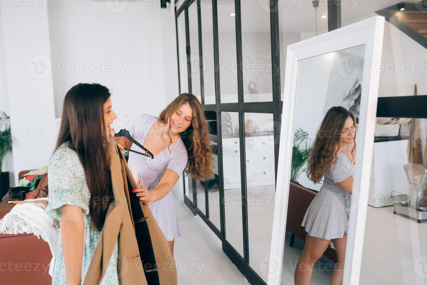 Two women choose and try on clothes at home photo