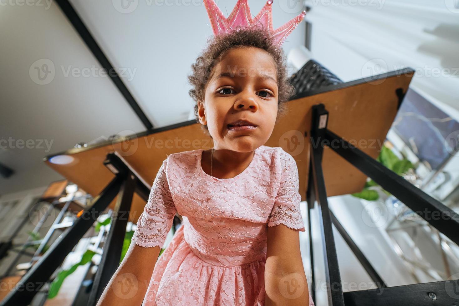 Little girl sitting on the floor grimacing at the camera photo