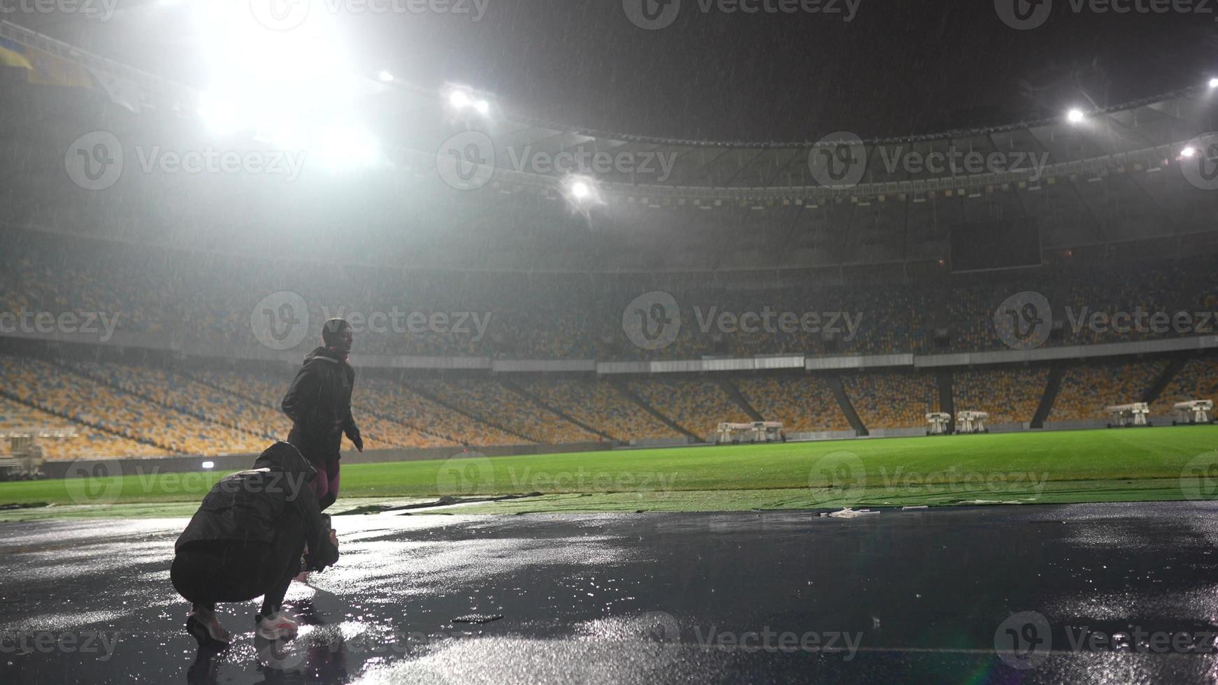 la gente practica deportes en el estadio nocturno cuando llueve foto