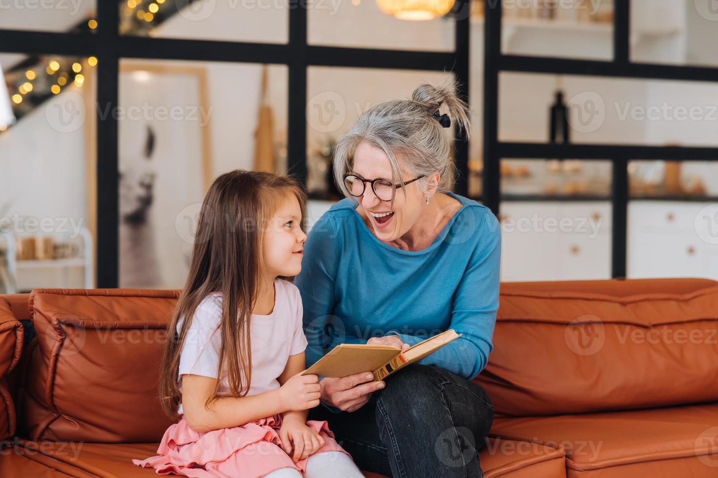 Nice elderly woman grandmother reading story to granddaughter. photo