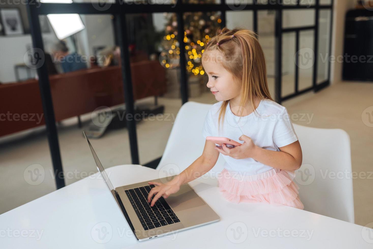 Little girl using tablet computer sitting at table photo