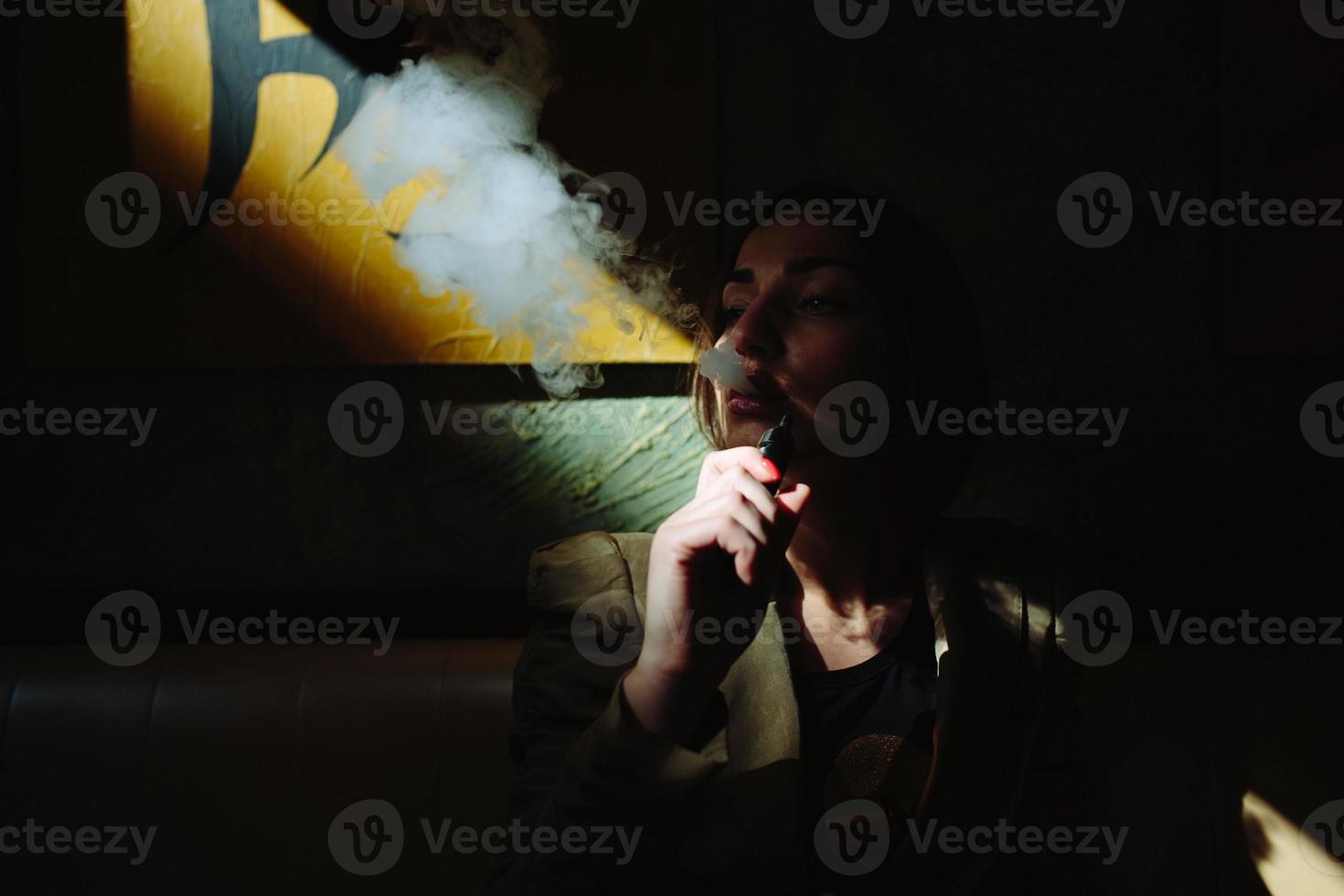 chica se sienta y fuma cigarrillo electrónico foto