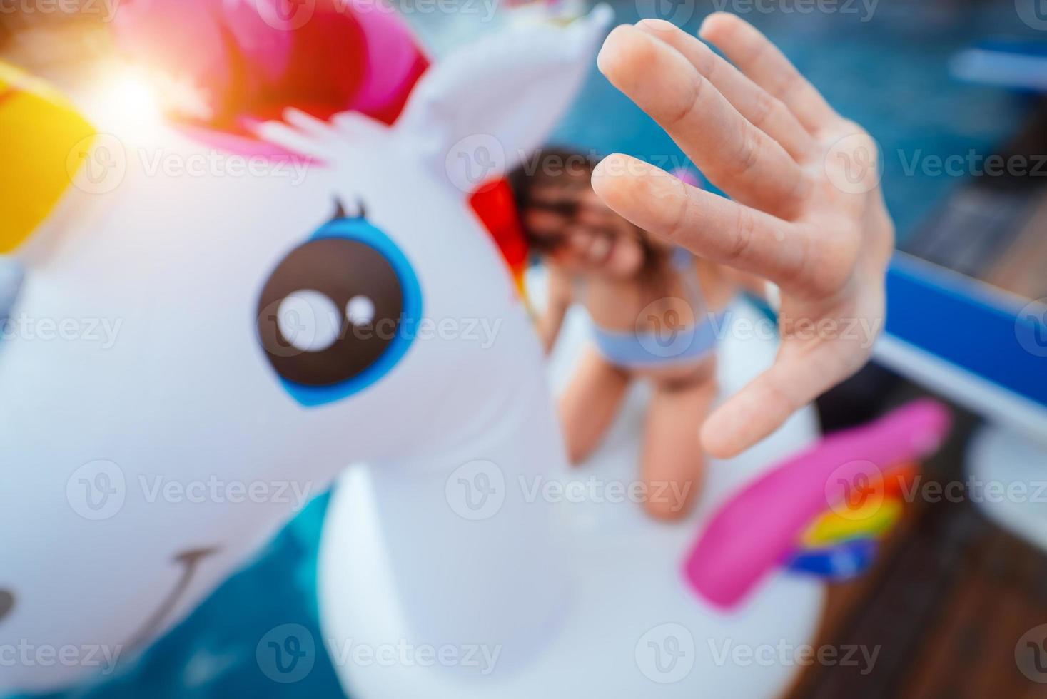 Happy young woman sitting on inflatable unicorn toy mattress photo