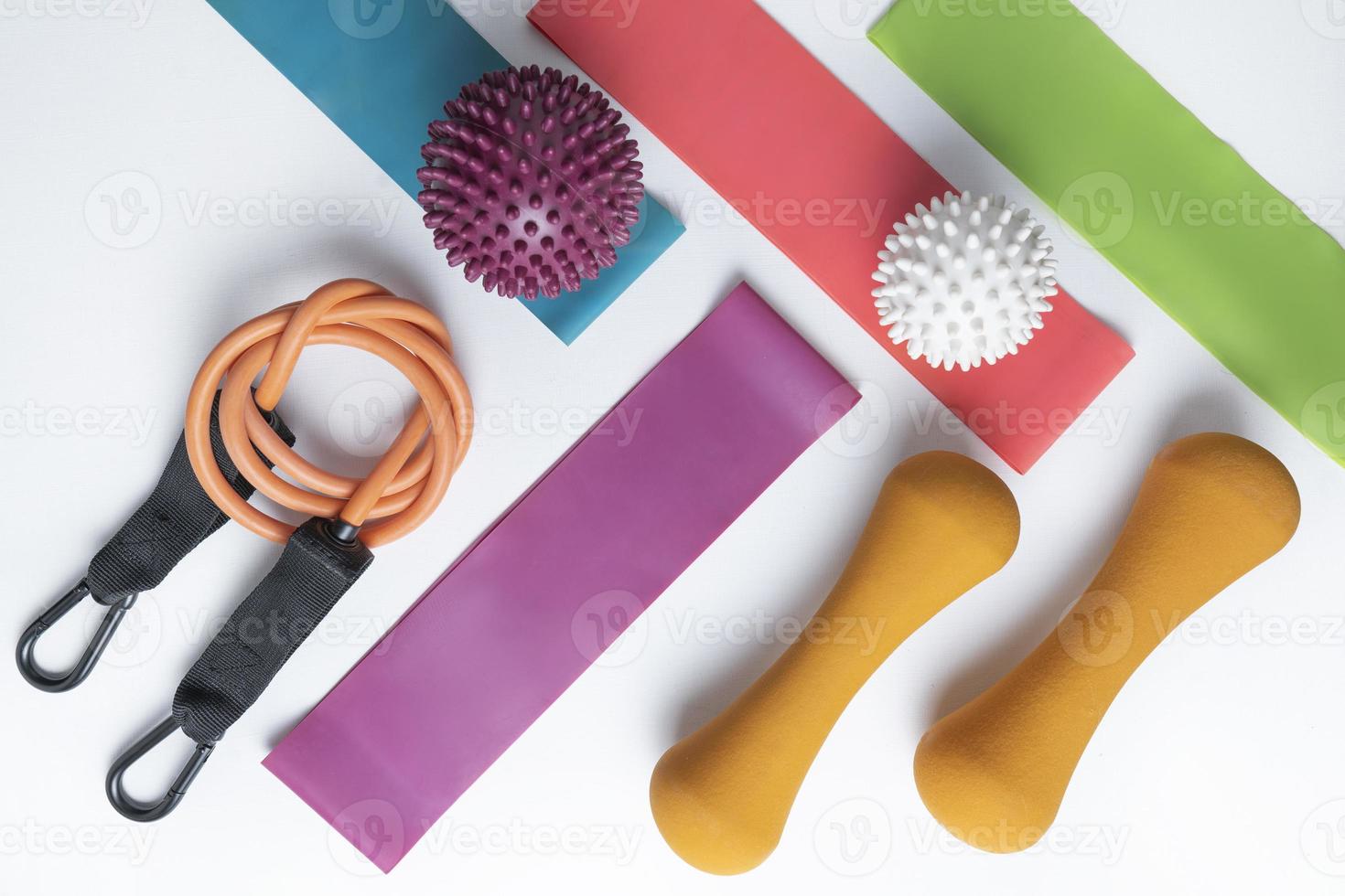 Different colourful equipment for fitness and sport exercises orange dumbbells and expanders, fitness balls and bands lying on a white background photo