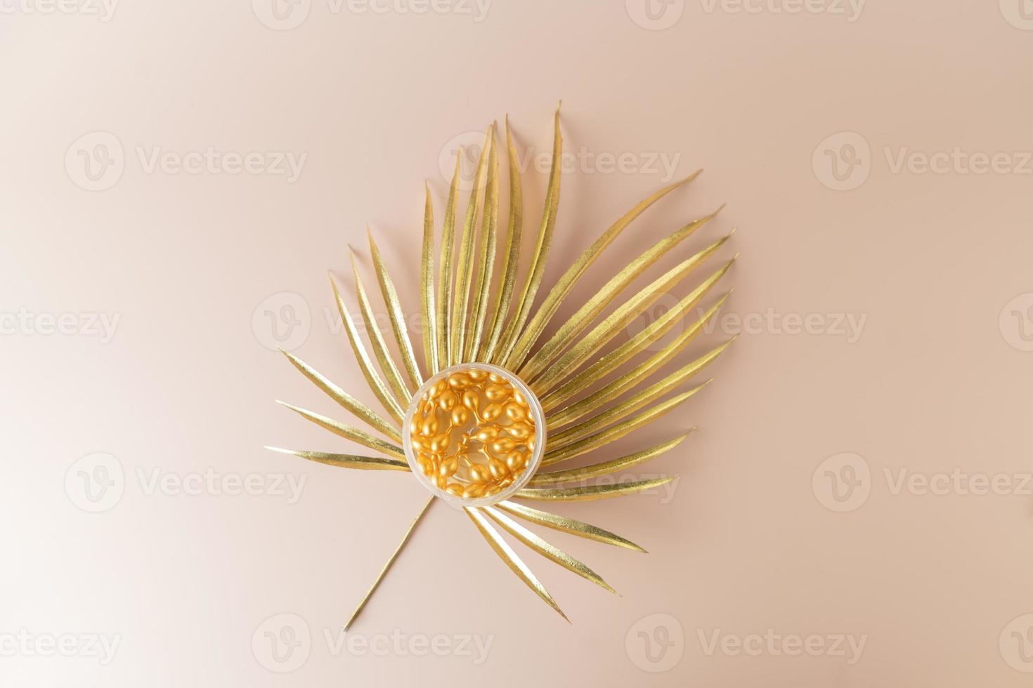 A face antiaging serum or oil in golden capsules lying in a box on a golden leaf photo