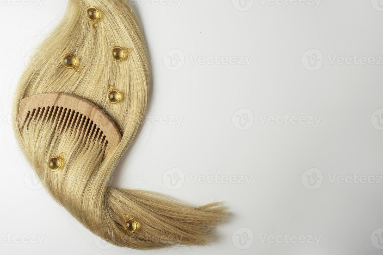 un aceite esencial natural o suero para el cuidado del cabello en cápsulas doradas sobre un cabello rubio. concepto de cuidado y alisado del cabello foto