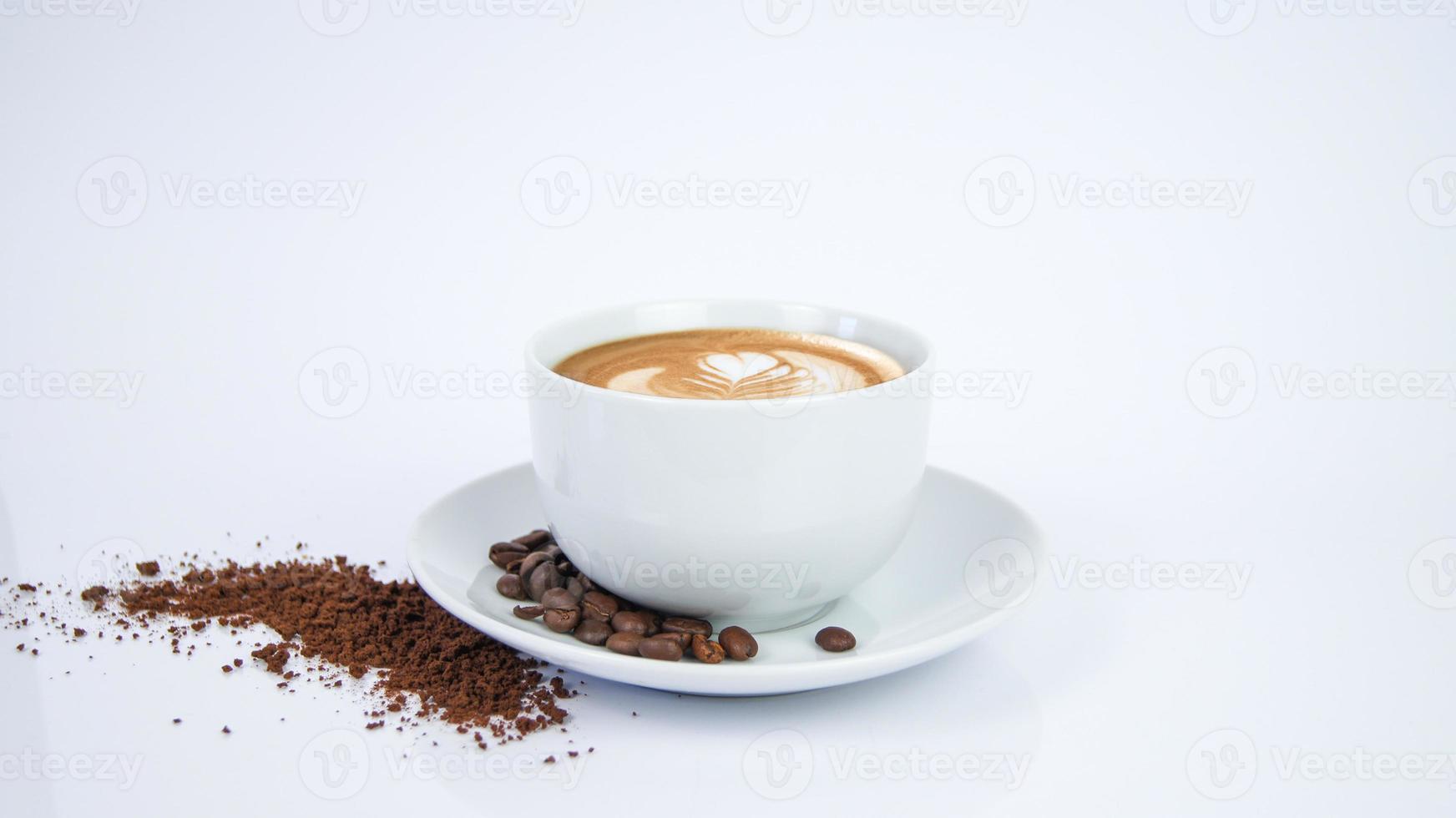 White Cup of Mocha Latte Coffee with Leaf Artwork made by Barista on porcelain plate with coffee seeds and powder on white background. Render Graphic for Cafe Store and Restaurant. photo