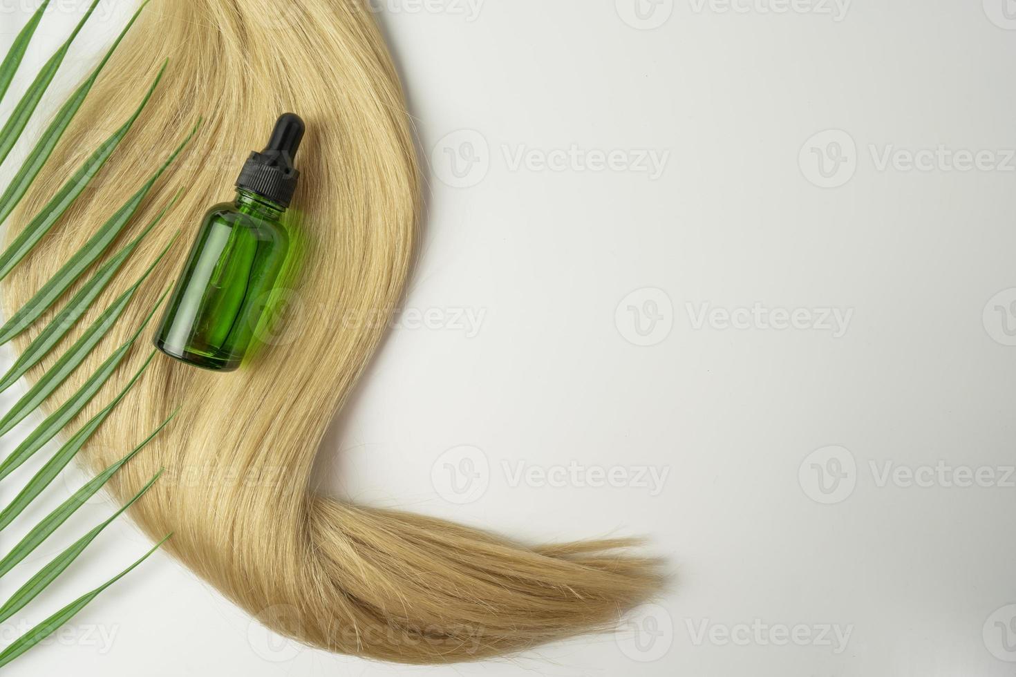 A natural oil or serum for hair care lying on a ply of blonde hair photo